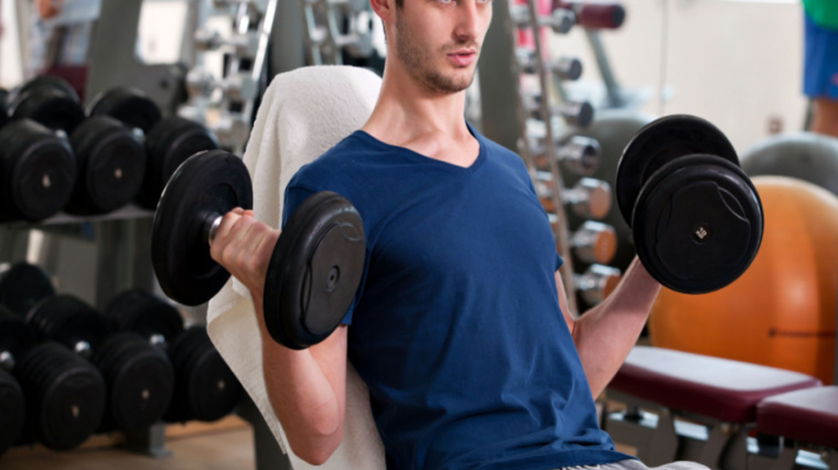 person in gym curling dumbbells