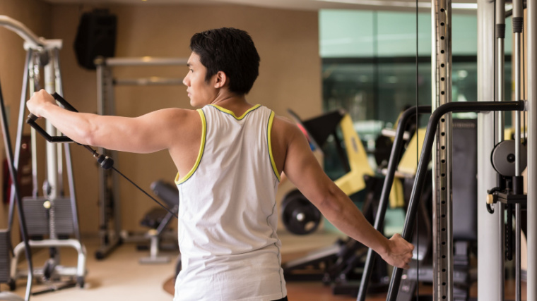 person in gym doing cable shoulder exercise