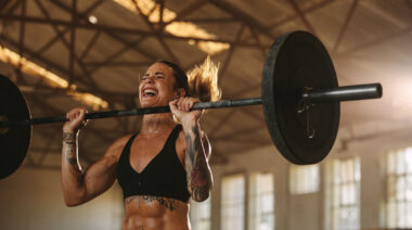 Long-haired person struggling to lift barbell