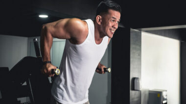 Muscular person in gym performing bodyweight dip exercise