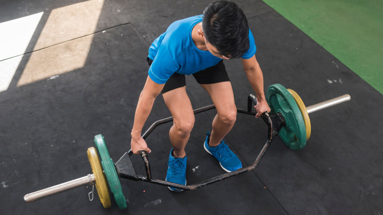 person in gym doing trap bar deadlift