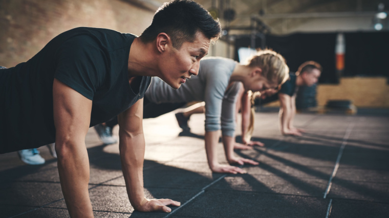 people in gym performing push-ups