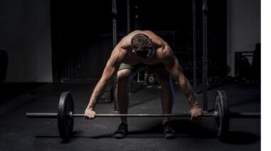 Muscular person in gym preparing to perform barbell row.