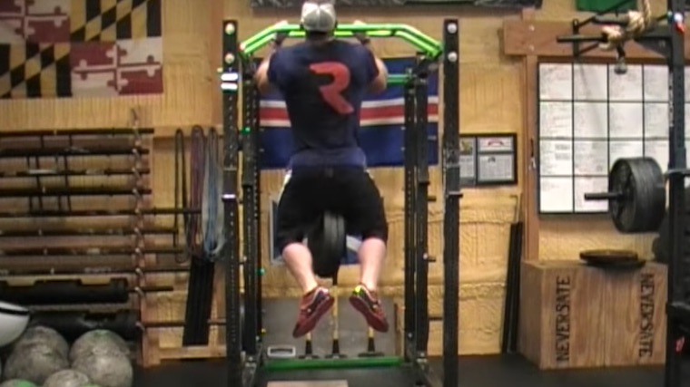 muscular person performing pull-up with weights