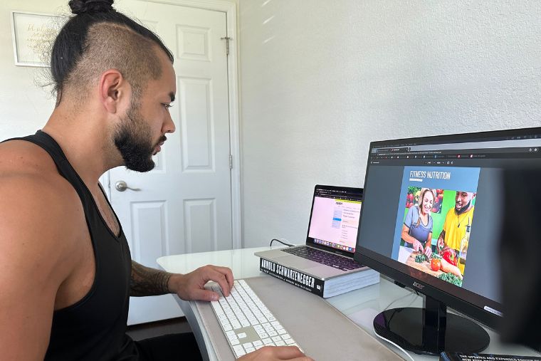 A young man reading a digital textbook from the ISSA Nutritionist course on his computer