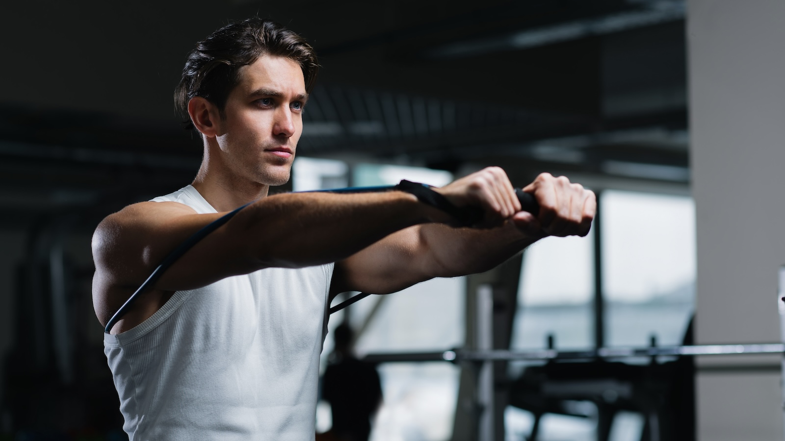 Man performs a resistance band chest press while looking ahead.