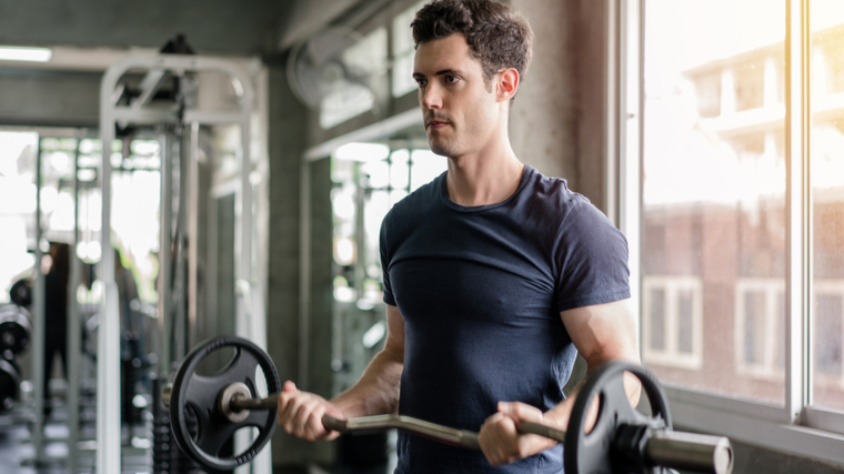 Man in gym curling barbell