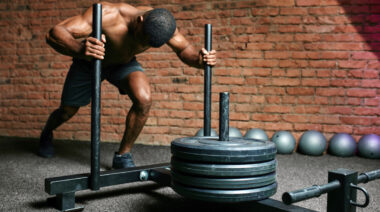 person pushing weighted sled in gym