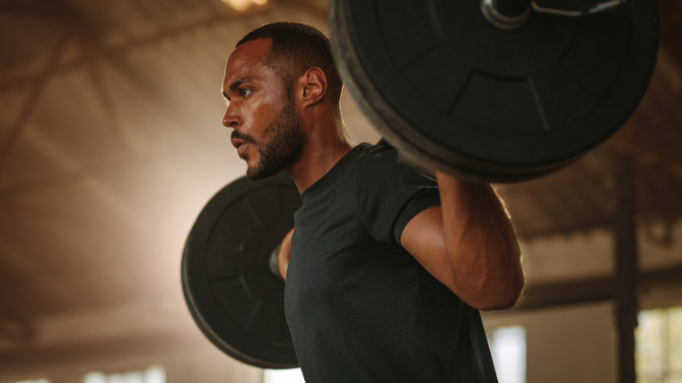 Man focused performing barbell squat