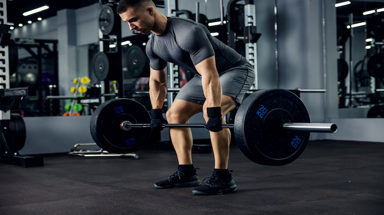 Person in gym holding barbell preparing to exercise