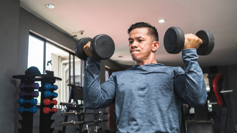 Man in gym lifting dumbbells