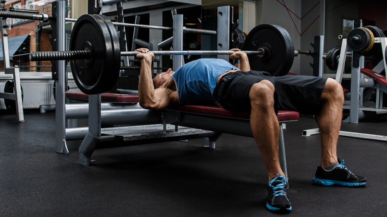 Muscular man performing heavy bench press exercise