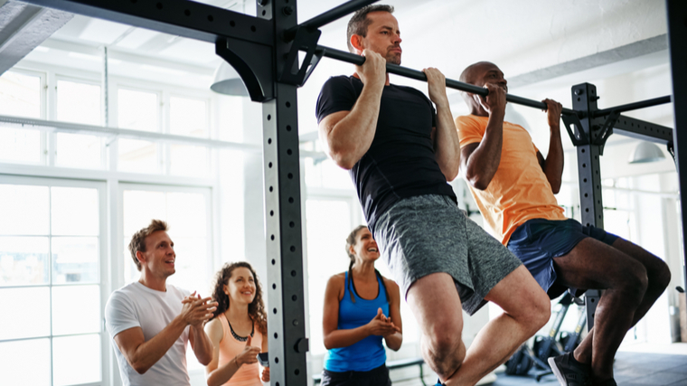 group of people in gym, two people performing chin-ups