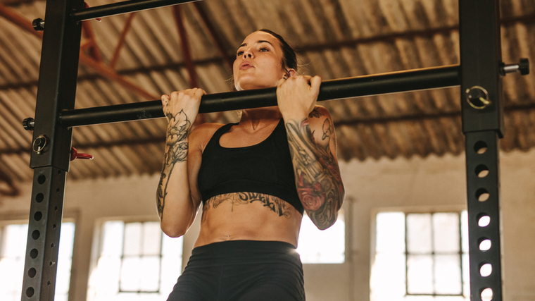 tattooed woman performing chin-ups